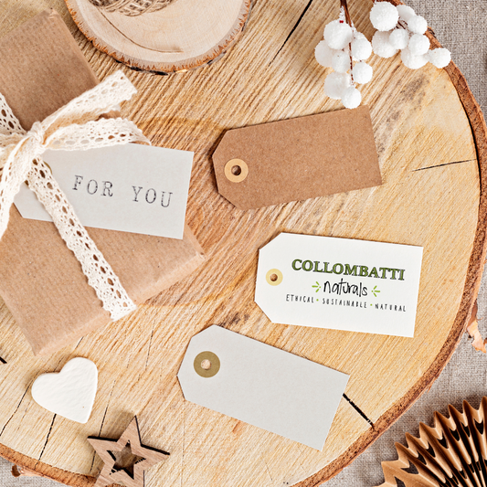 Collombatti Naturals Sustainable Gifts Guide to Help You Shop with a Conscience Blog cover photo brown paper wrapped gifts on a log and paper gift tags with the Collombatti Naturals Logo on the front