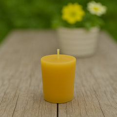 beeswax votive candle refill sitting on a wooden table with yellow flowers in the background