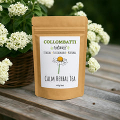 A brown kraft paper pouch of Collombatti Naturals Calm Herbal Tea, featuring a minimalist white label with a hand-drawn chamomile flower. The packaging highlights ethical, sustainable, and natural values. The pouch is placed on a rustic wooden table, surrounded by delicate white flowers in a woven basket, creating a serene and natural aesthetic