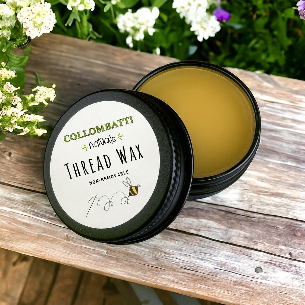 Collombatti Beeswax Thread Wax in an aluminium container on a wooden surface with flowers in the background