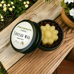 Beeswax thread wax conditioner in a black container with 'Collombratti Naturals' branding on a wooden surface.